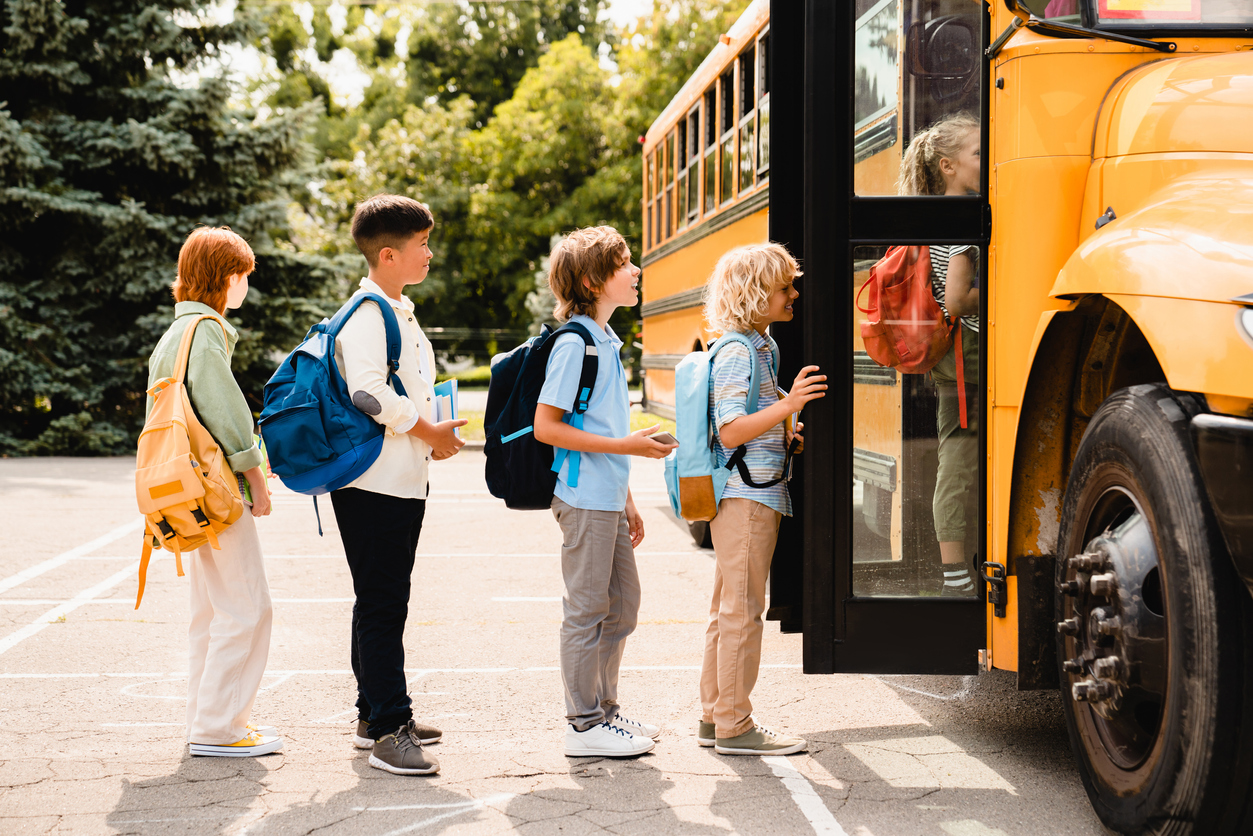 children lining up to get on a schoolbus